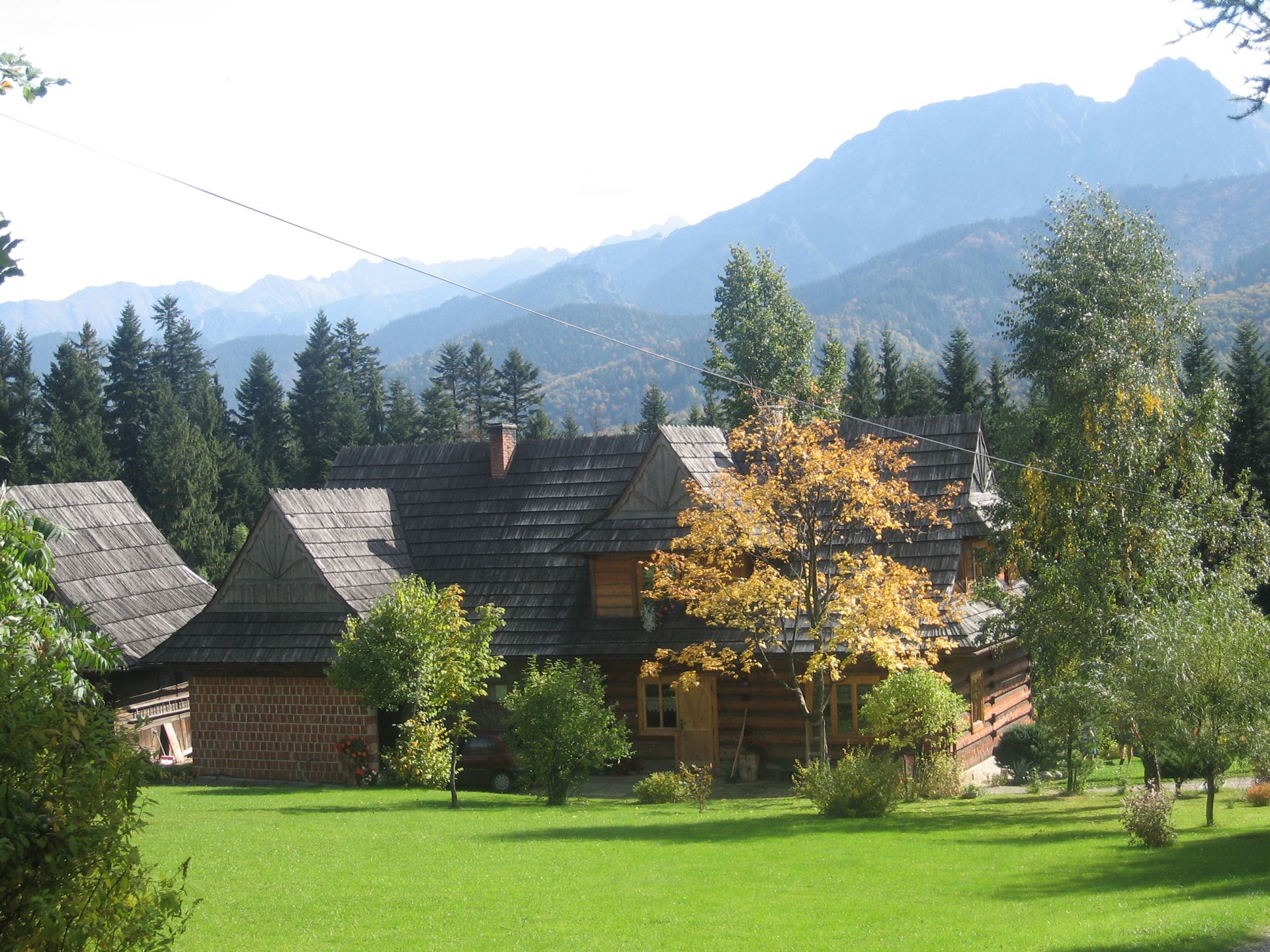 Zdjęcie przedstawia krajobraz górski z widokiem na budynek drewniany góralski jesienią