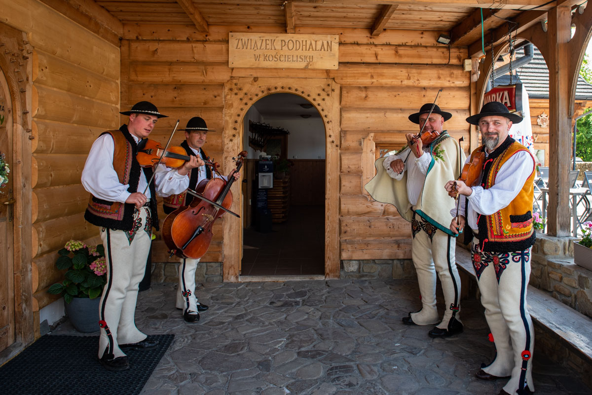 zdjęcie przedstawia muzykantów góralskich przed wejściem do domu ludowego w Koscielisku